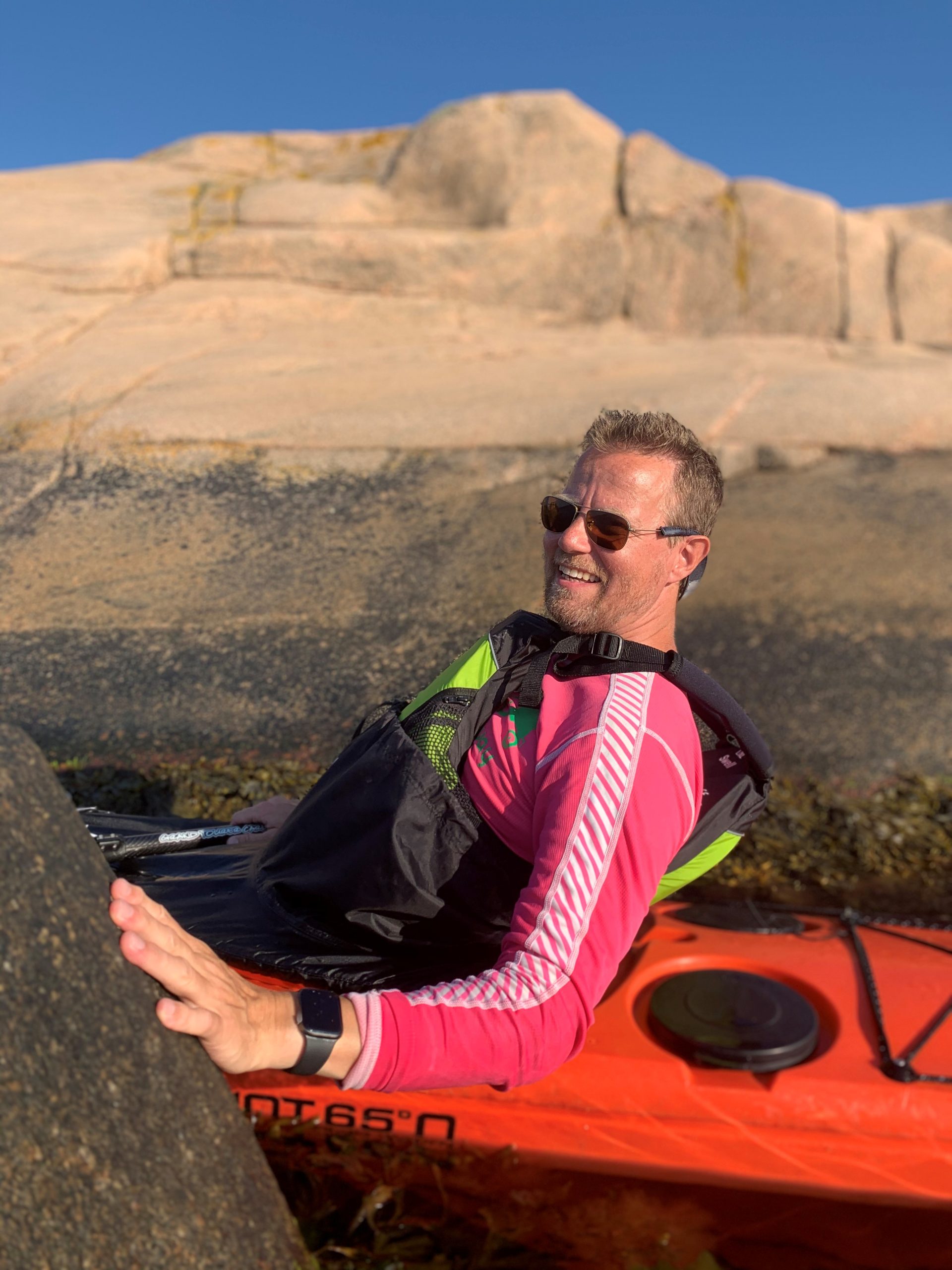 En man sitter i en kajak mellan två klippor vid vattnet.