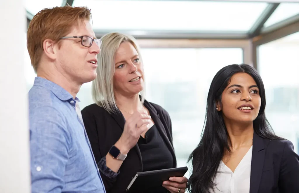 En man och två kvinnor, står leende och blickar bortåt.